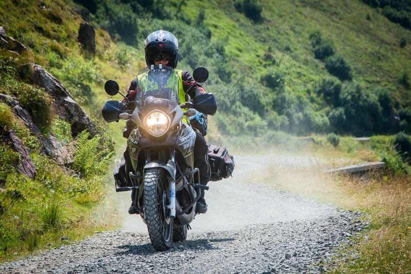 A motorcyclist rides on a gravel road