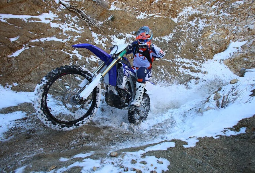 A Honda CRF450RX is going through a snow and ice trail