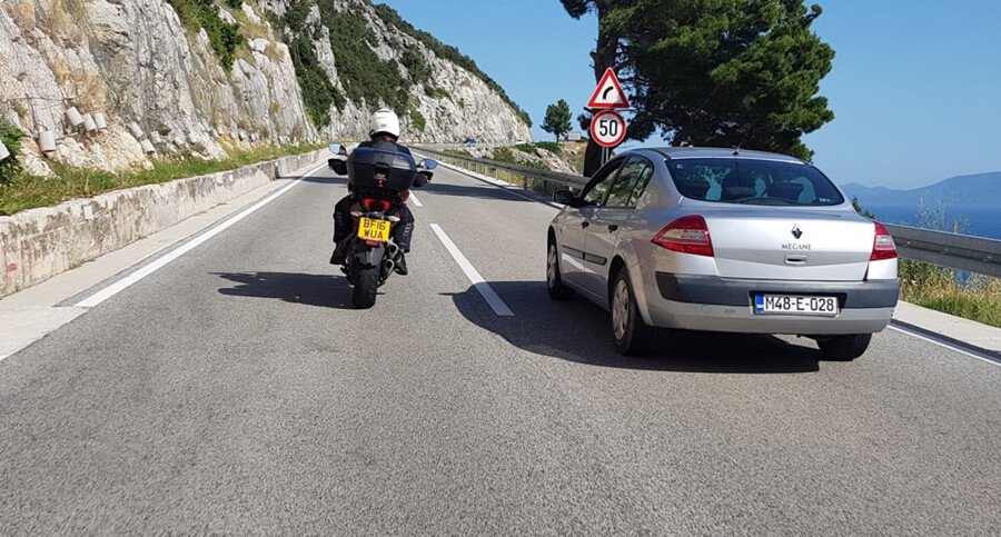 a motorcycle is passing a car on the road - How to Safely Pass Vehicles on a Motorcycle