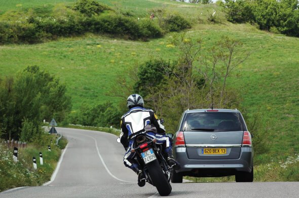 a motorcycle is trying to pass a car on the road