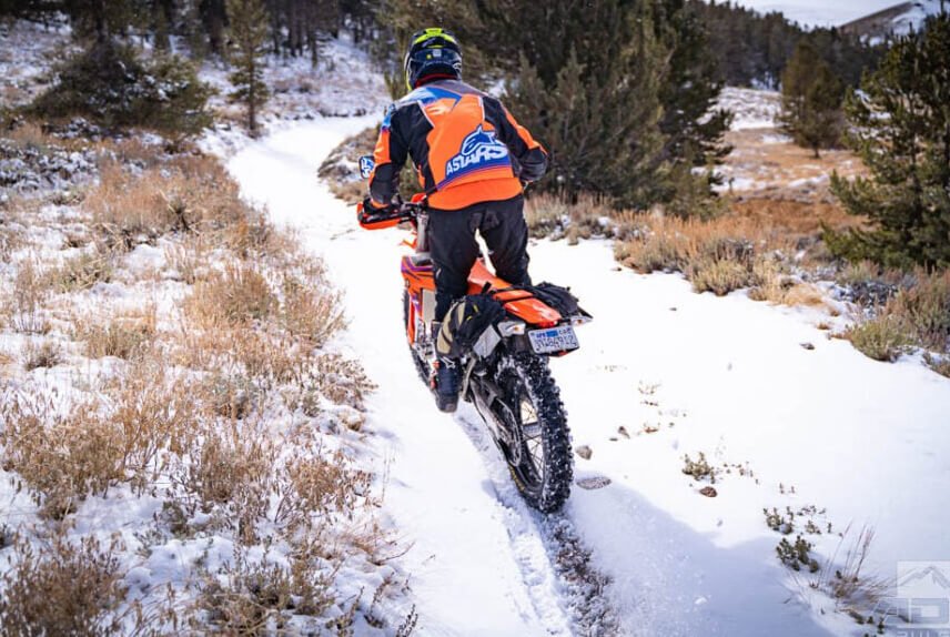 a rider is riding a KTM 500 EXC-F on a snow and ice trail