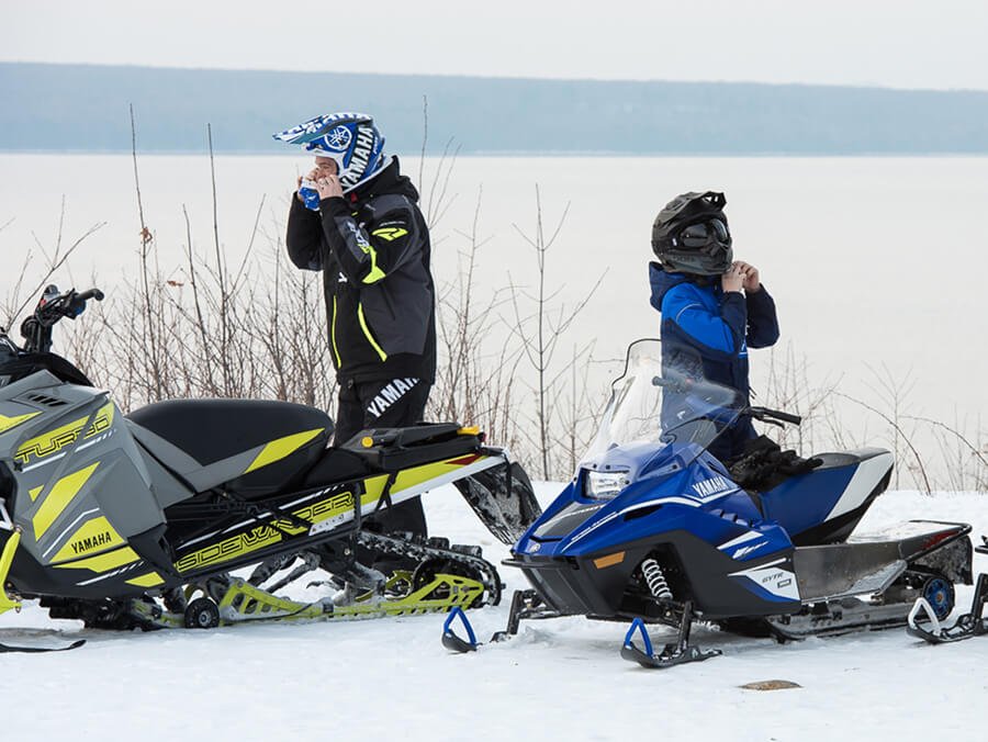 A young child is riding snowmobile with an adult - Snowmobile Age Requirements and Rules