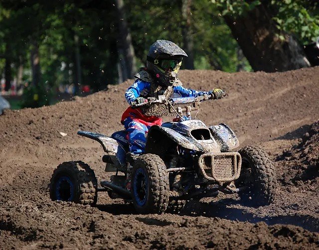 A young boy riding a DRR youth ATV in the mud trail